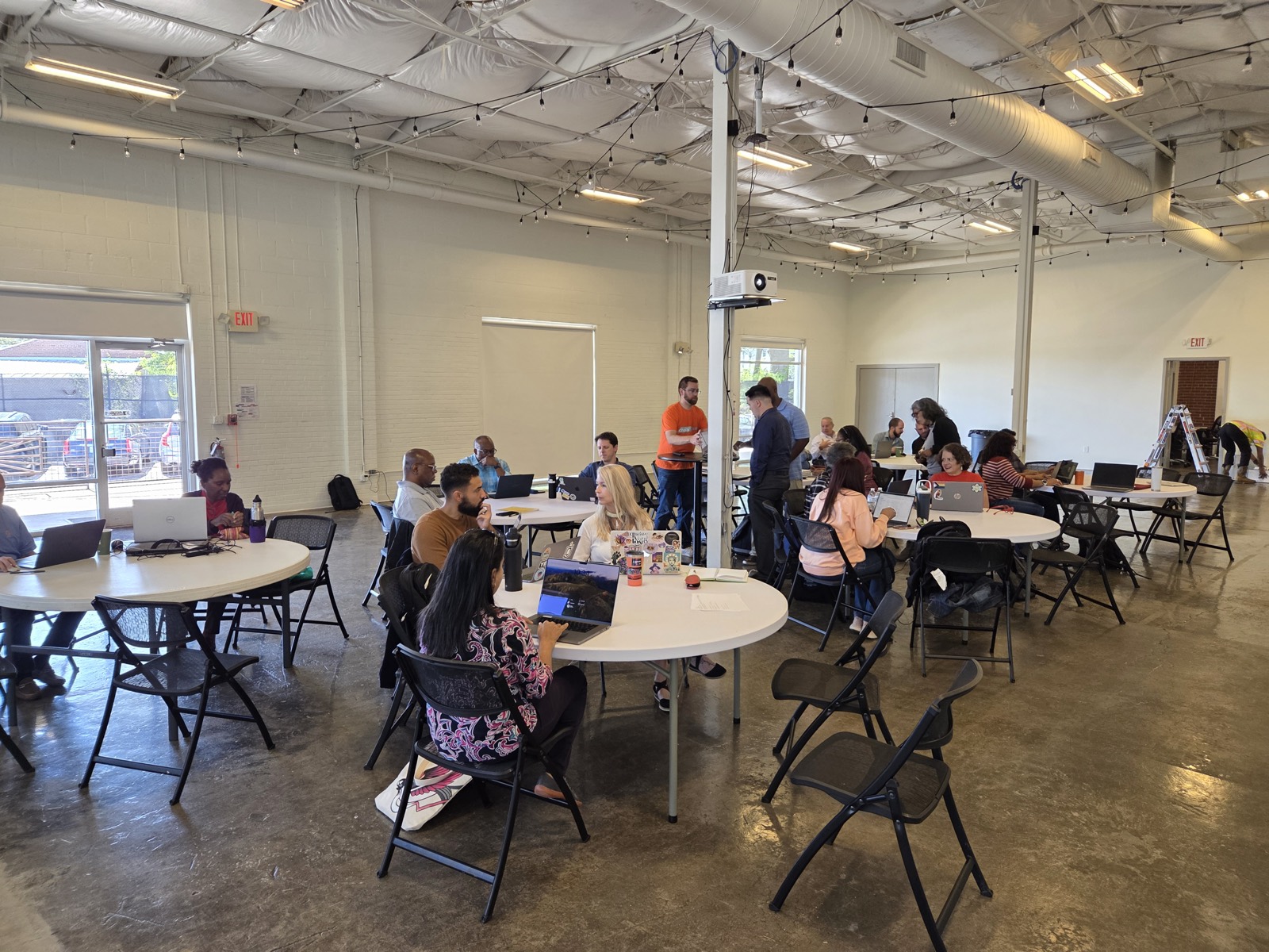 Wide view of the session space with operators at tables, laptops open