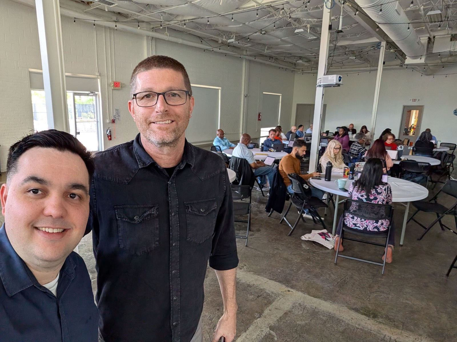 Host and facilitator at an AI for Changemakers LEAP session, a full room of operators working behind them